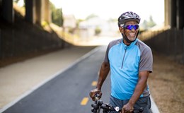 A smiling middle-aged male cyclist pausing for a break by the roadside.