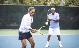Happy older couple playing tennis