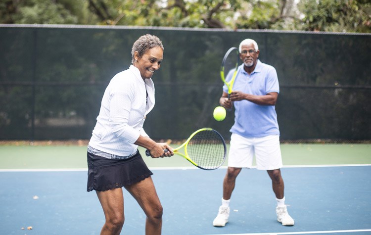 Happy older couple playing tennis