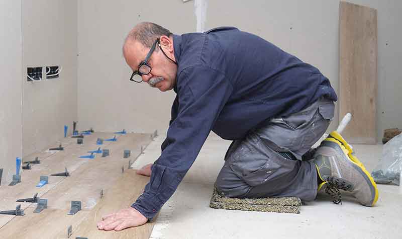 A floor layer working on his knees