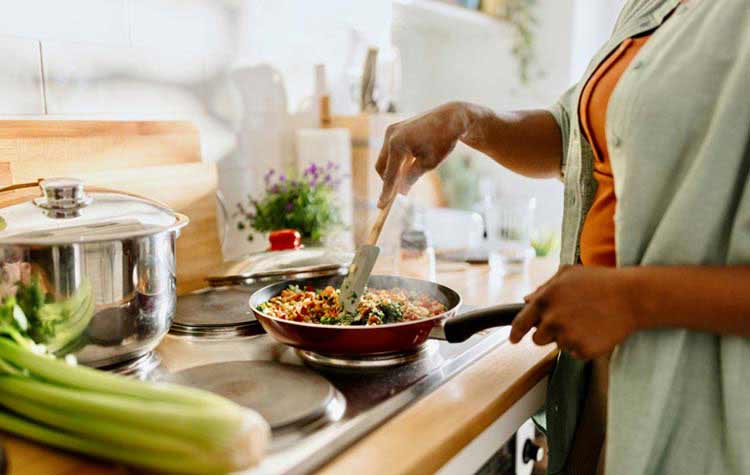 Woman cooking vegetables in a frying pan