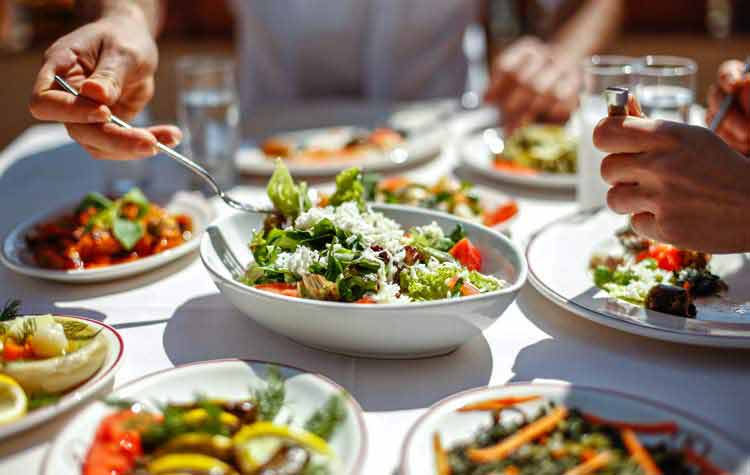 Couple Eating Lunch with Fresh Salad and Appetizers