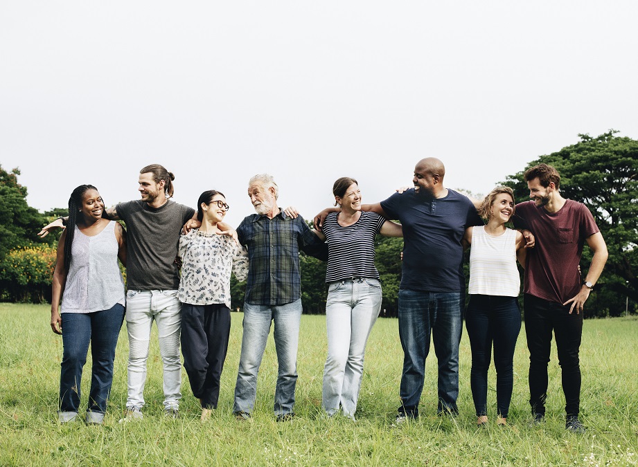 A group of happy people standing in a field with their arms around each other