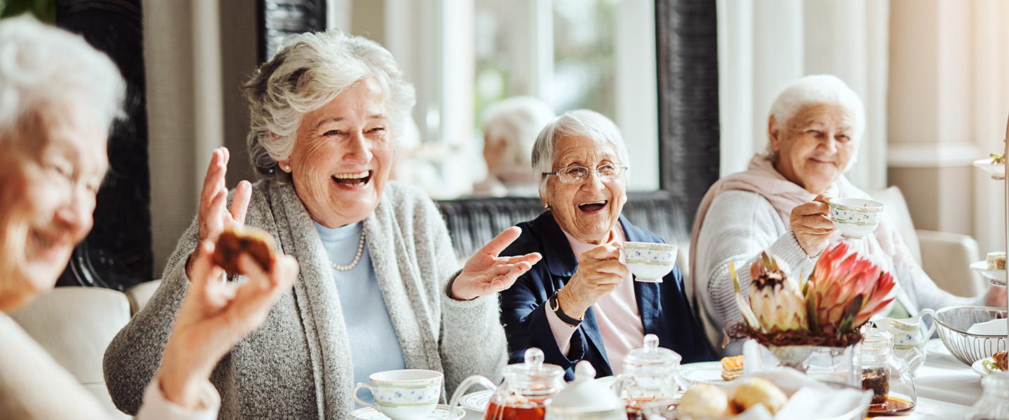 Four elderly women enjoying afternoon tea