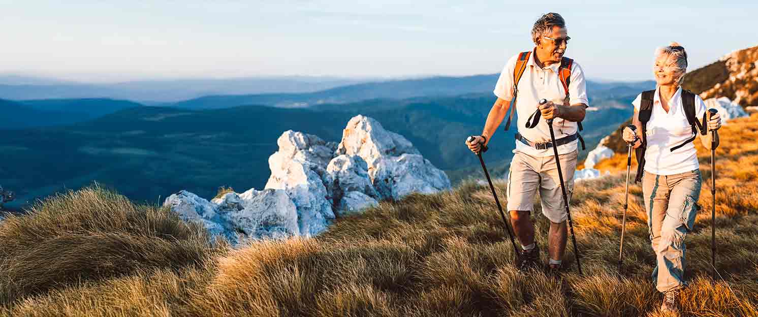 Two people hiking on the coast with walking poles