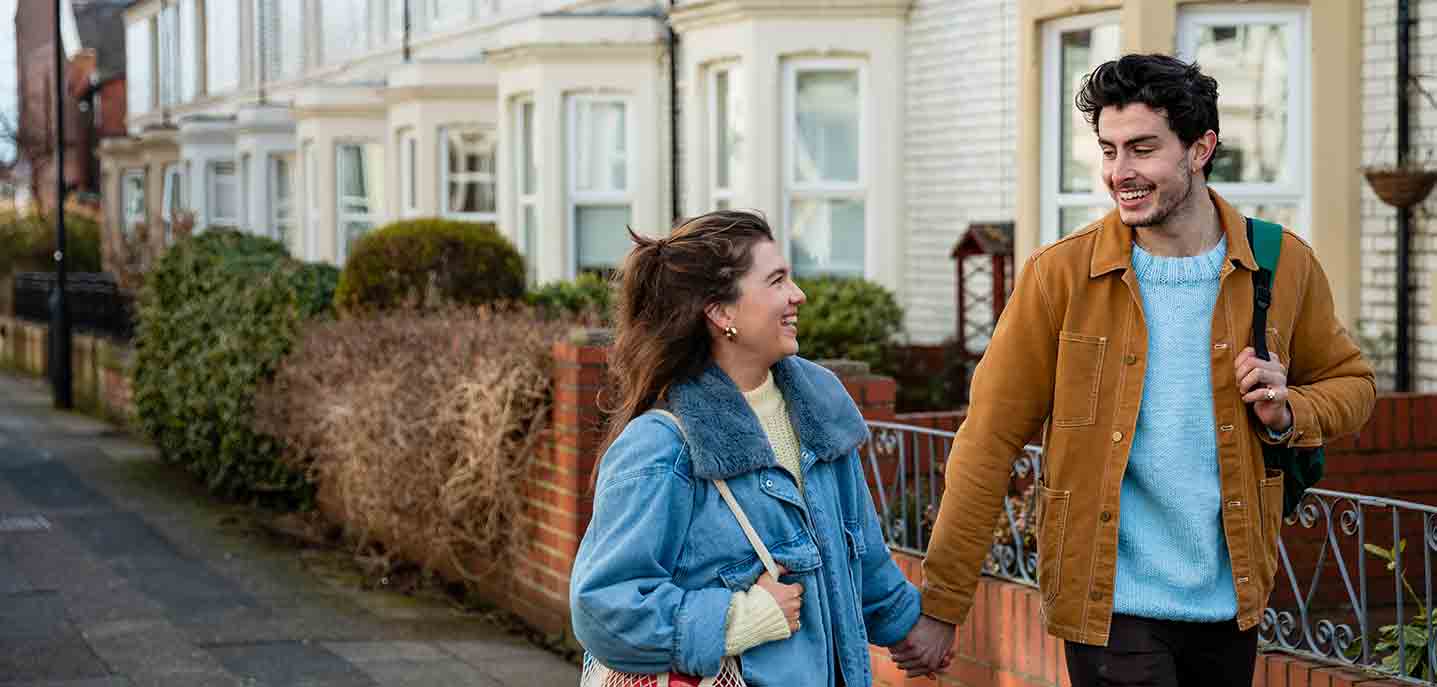 Two people walking down the road holding hands