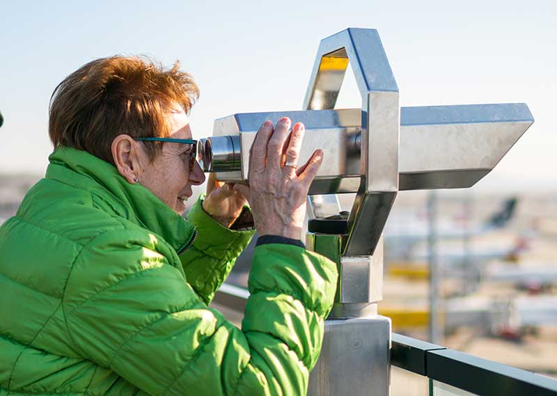 An older lady looking out to see with some binoculars
