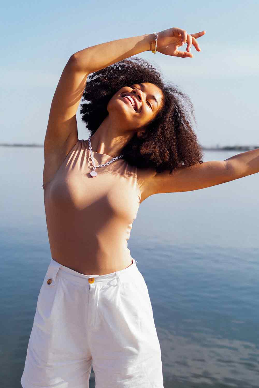 A woman waving her arms by the sea