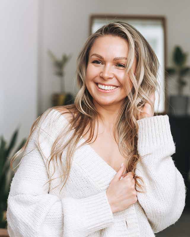 A woman in a jumper smiling at camera