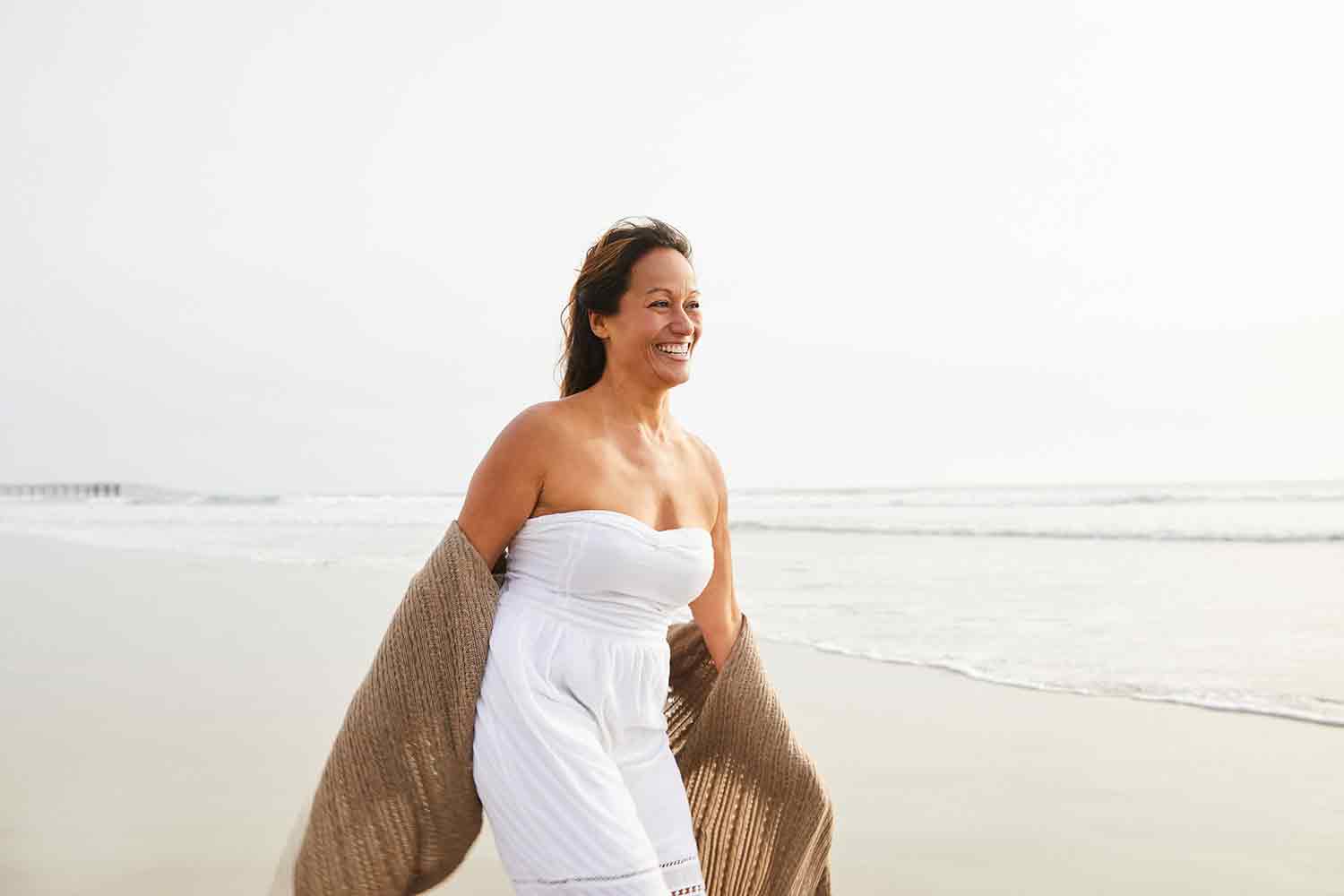 A woman in a summer dress walks along the beach