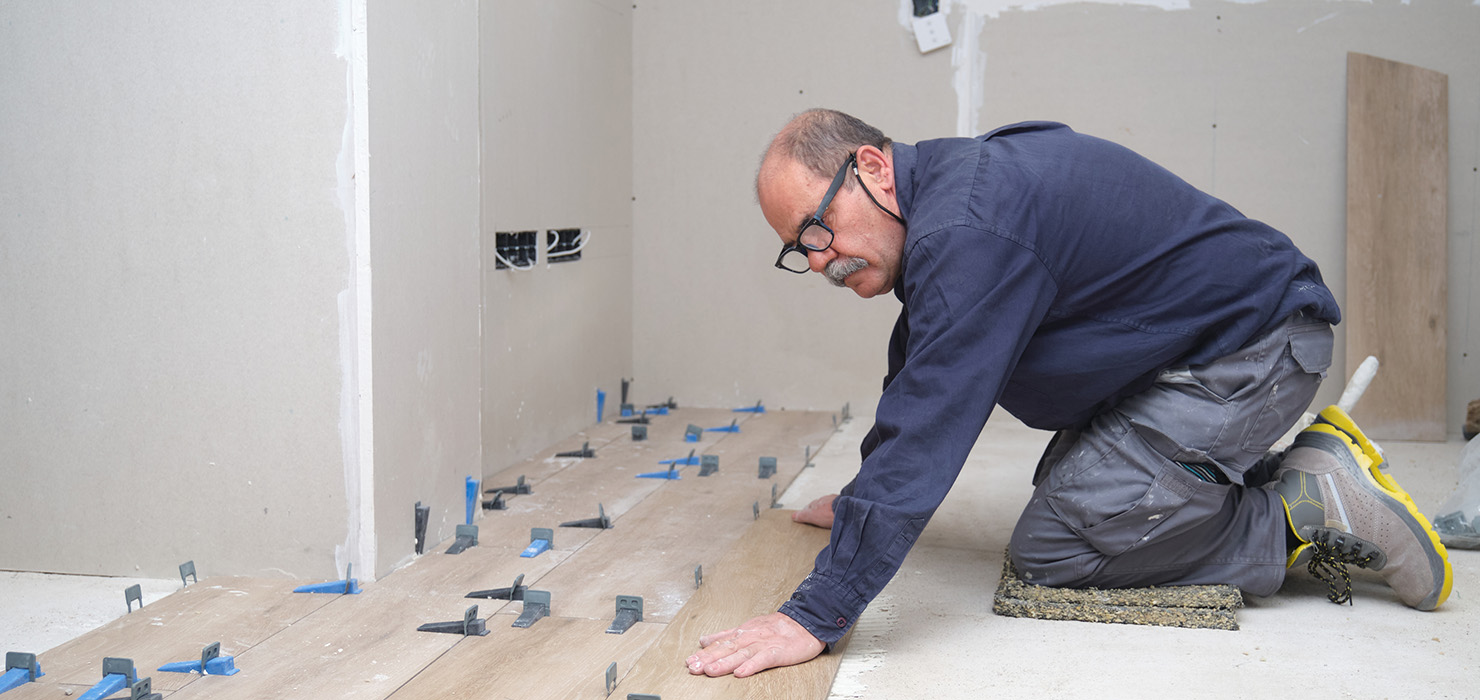 Man on his knees laying wooden flooring