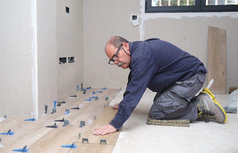 Man on his knees laying wooden flooring