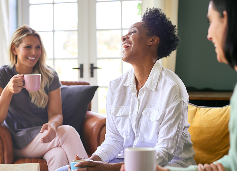 Three women laughing on a sofa