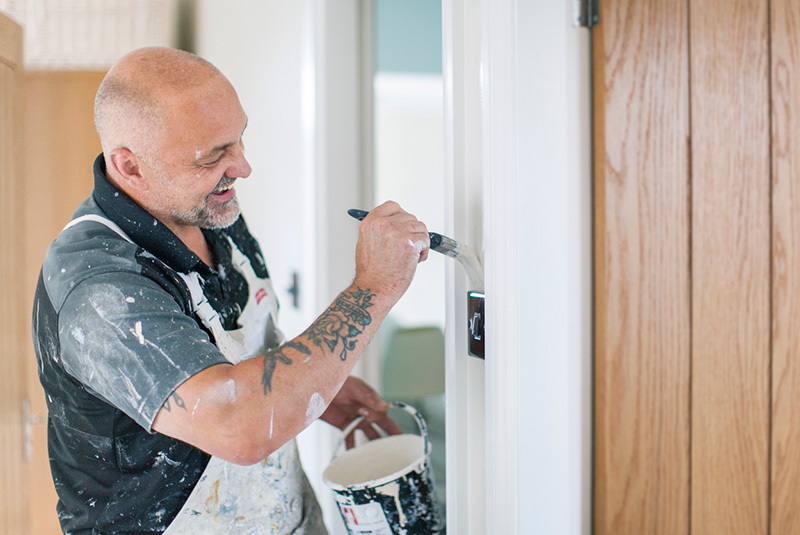 Man smiling whilst painting the walls