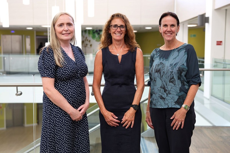 Three people standing in a hospital atrium