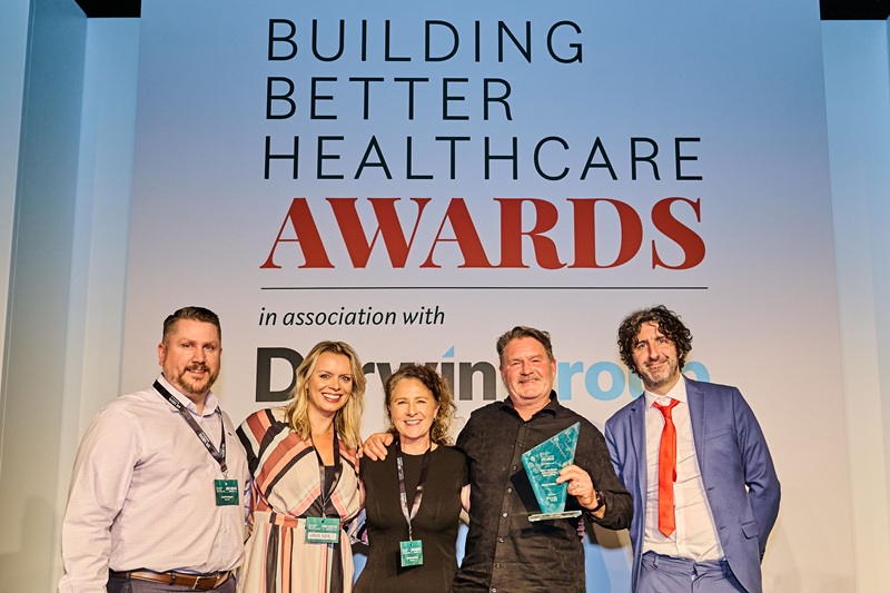 A group of people onstage collecting an award from comedian and compere Mark Watson