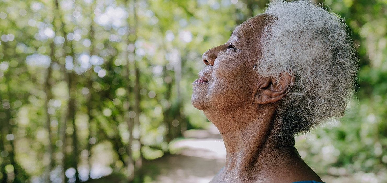 Elderly woman breathing in deeply outdoors