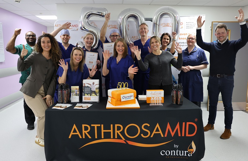 A group of people celebrating with cake and balloons which spell out '500'