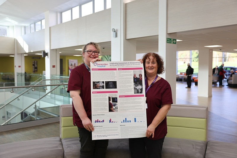 Two sonographers holding a research poster