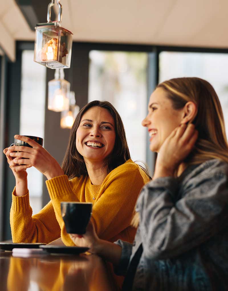 Two women holding cups and chatting