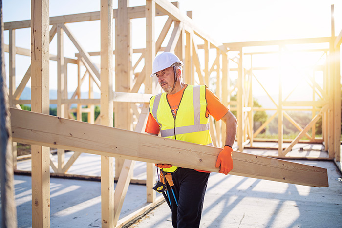 A man carrying a plank of wood on a building site