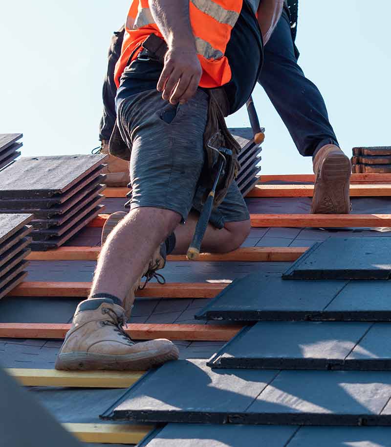 Two men climbing on a sloping roof