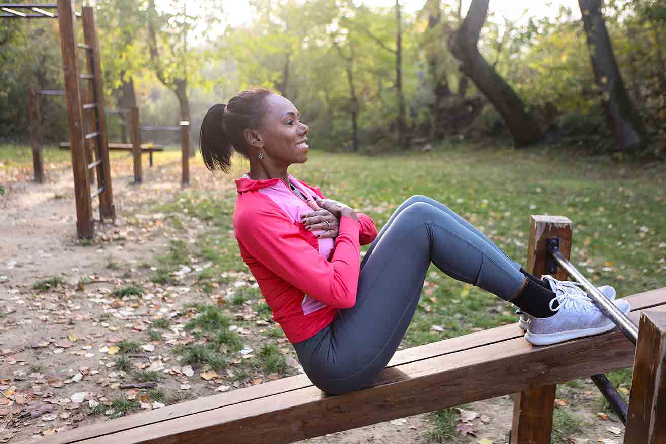 Woman doing sit ups with her toes under a bar