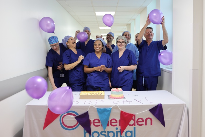 A group of operating theatre staff celebrating with cake and balloons