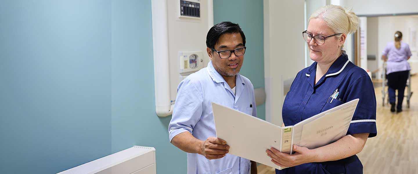 Two colleagues discussing notes in a folder