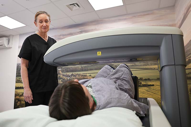 One of our imaging staff standing next to the DEXA scanning machine