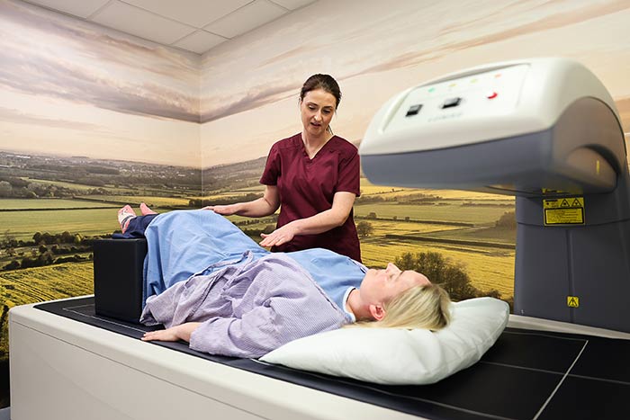 A member of the imaging team standing next to the DEXA scanning machine