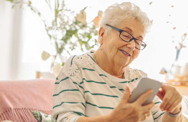 An older lady in glasses reading her phone