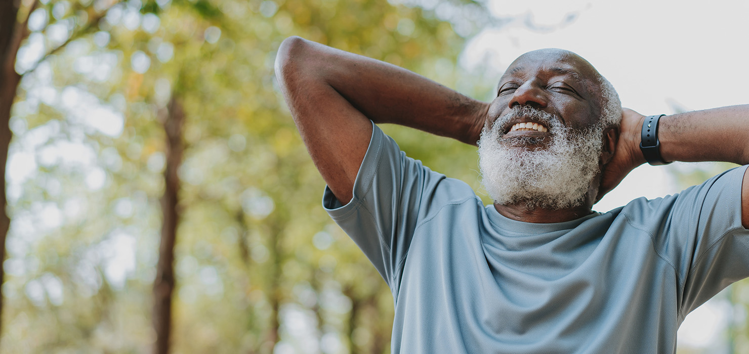 Senior man breathing deeply and smiling outdoors in a park