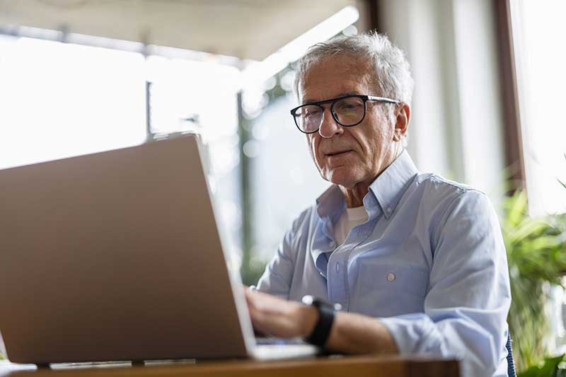 A man in glasses looking at his laptop