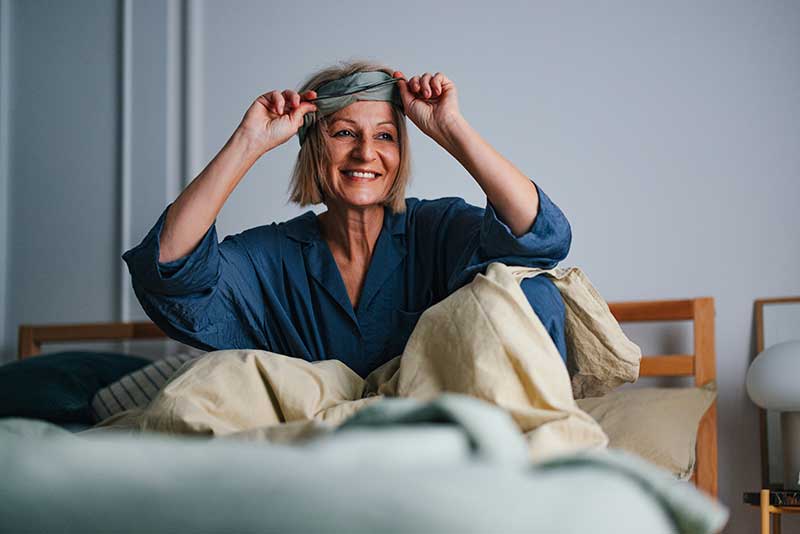 A older woman waking up in bed after a good sleep