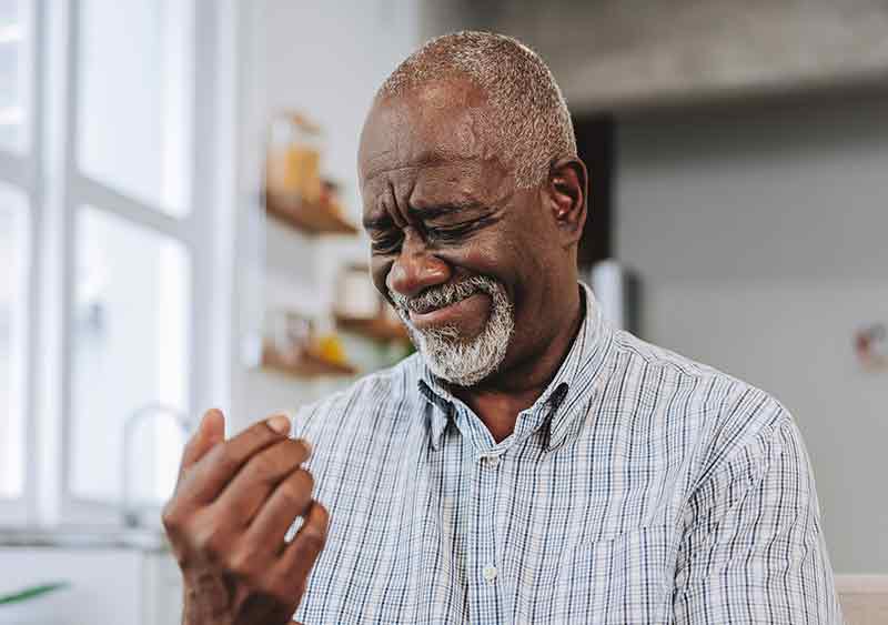 A man looking at his hands affected by Raynaud's syndrome